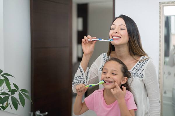 Una madre y sus dos hijo que se cepillan los dientes en el baño Una madre y sus dos hijo que se cepillan los dientes en el baño