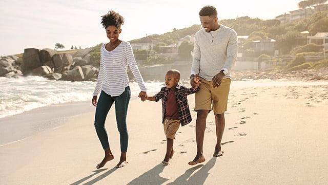 happy family of three walking on the beach