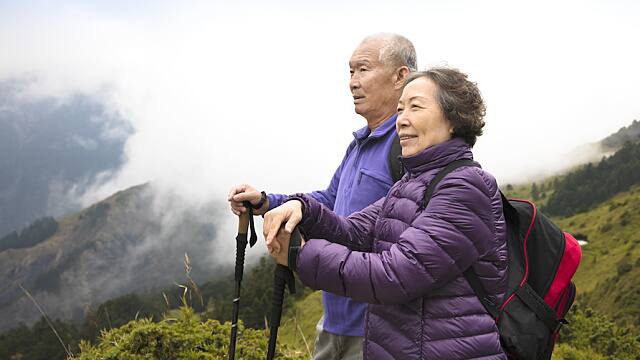 happy asian senior couple hiking on the mountain