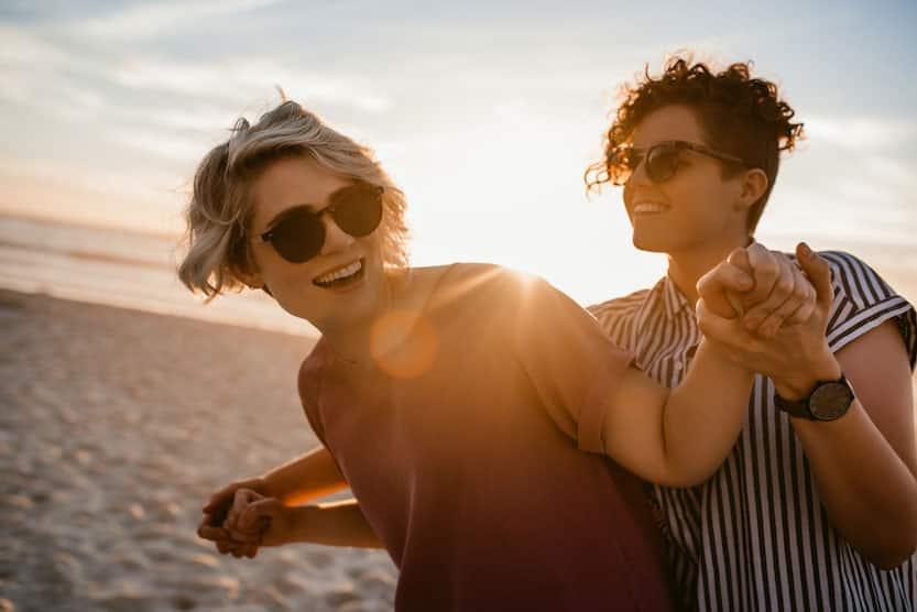 Laughing couple dancing together on a beach at sunset