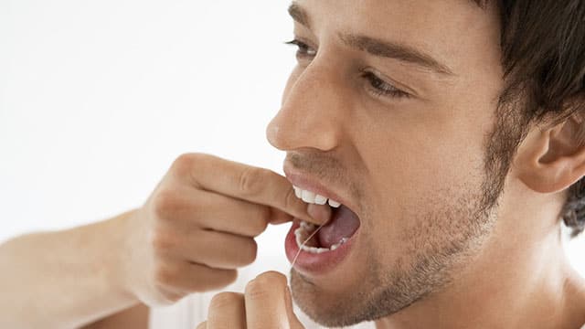 Young man flossing his teeth