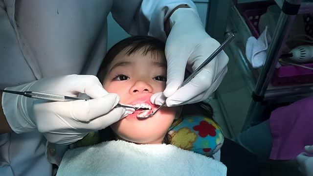 A kid is being check up by the dentist in the office