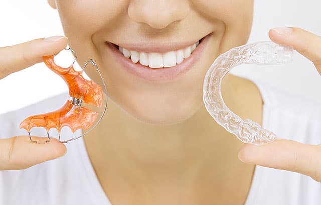 A young woman holding a dental retainer and a tray