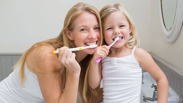 Mother and daughter brushing their teeth