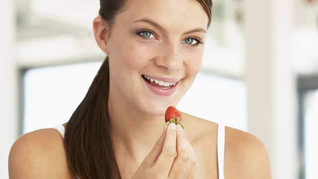 Young woman tasting strawberry