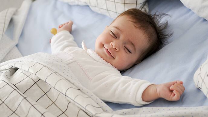 smiling newborn sleeping in crib