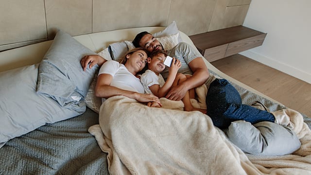 Young family in bedroom looking at cell phone