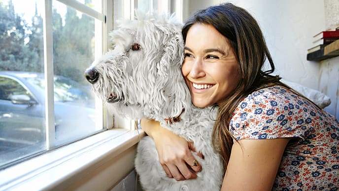 Mujer sonriendo mientras abraza a su perro