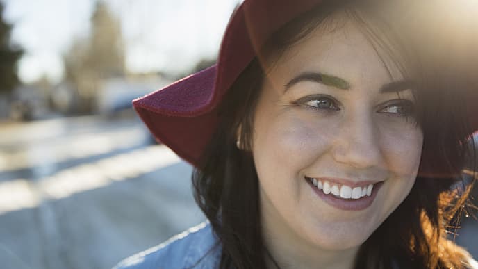A woman wearing a hat smiling brightly