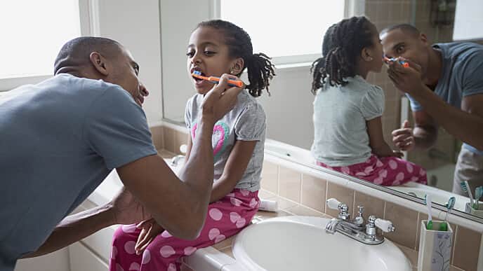 Padre enseñándole a su hijo a lavarse los dientes