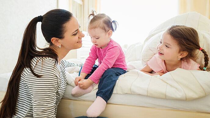 Dos hermanas dentando y su mamá riendo