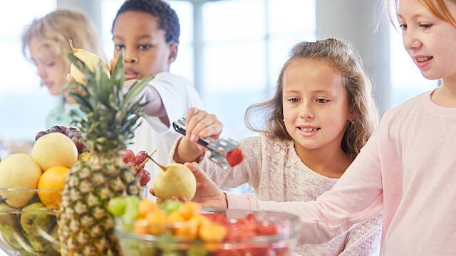 Children are picking up fruits at the buffet