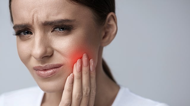 mujer con dolor de dientes