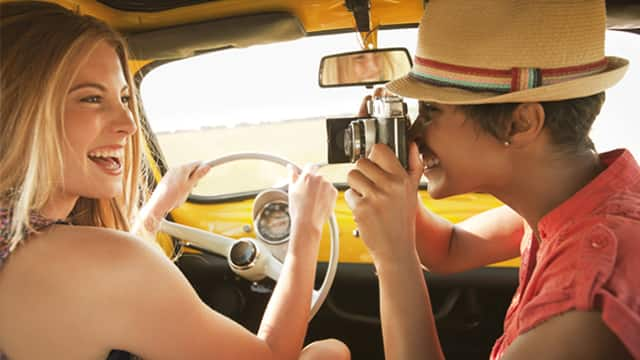 two women in a car smiling brightly while taking a picture