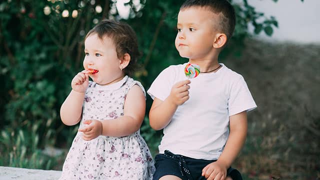 Kids eating candy outdoors Two children eating candy outdoors in the summer