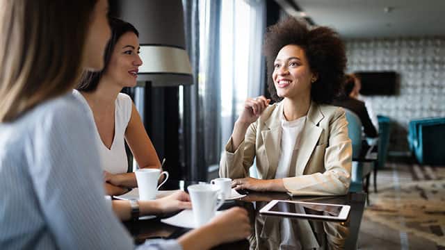 three women smiling while having a meeting