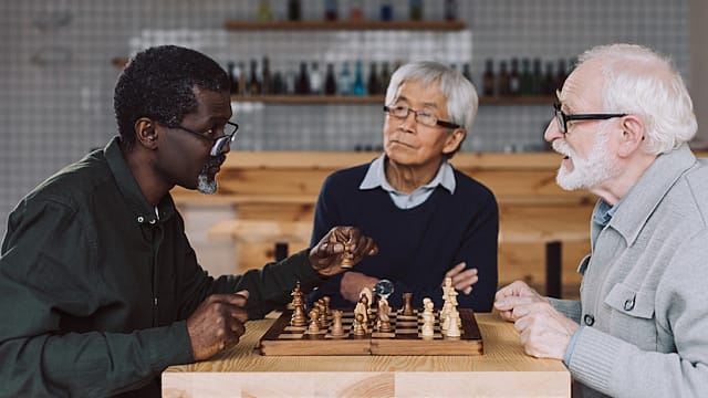 three senior friends playing chess