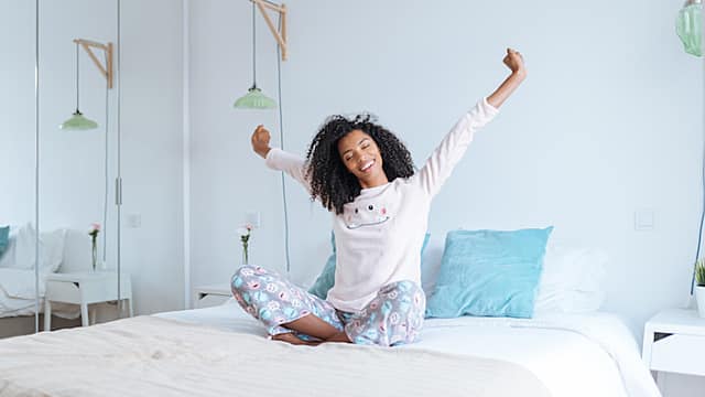 Happy beautiful young black woman relaxed sitting in the bed 