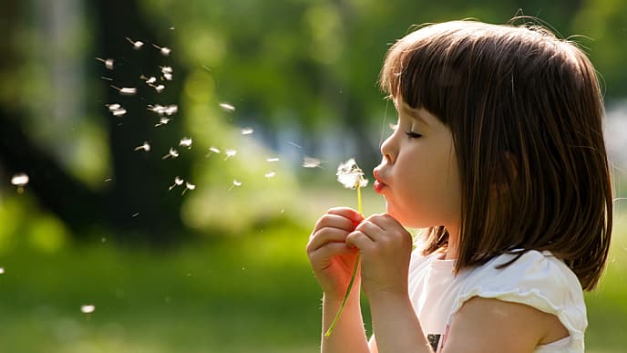 Niña soplando un diente de león