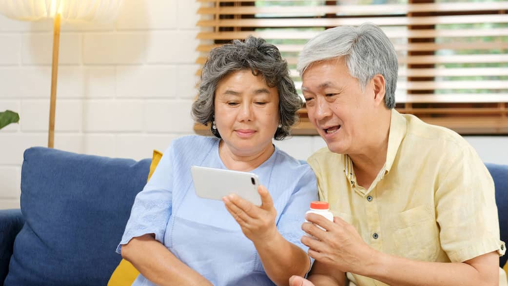 Senior asian couple holding bottle of pill make video conference call to doctor, pharmacy consulting about medical health care for old, retirement, elderly people, Senior couple health and technology