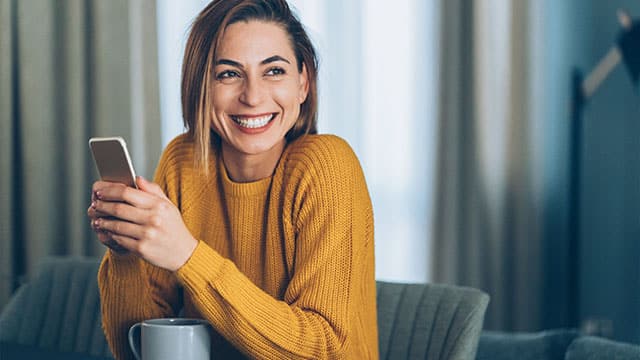 Woman is holding a phone and smiling