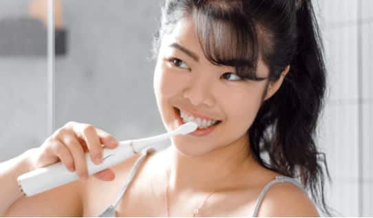 Woman brushing her teeth using Colgate Electric toothbrush