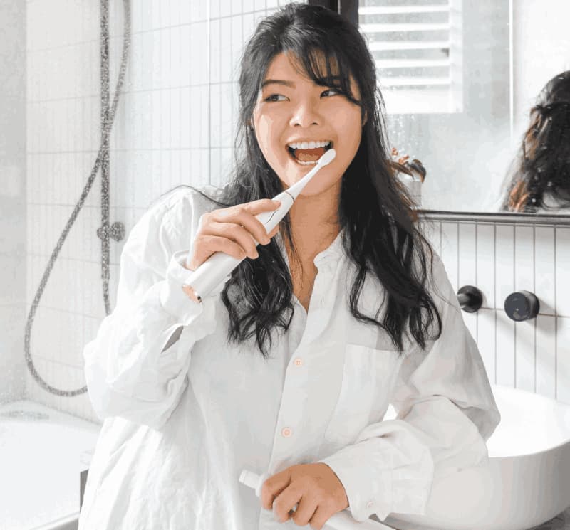 Woman brushing her teeth using an electric toothbrush