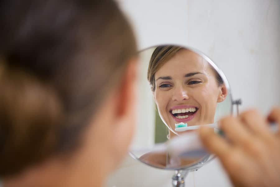 woman brushing teeth with electric toothbrush