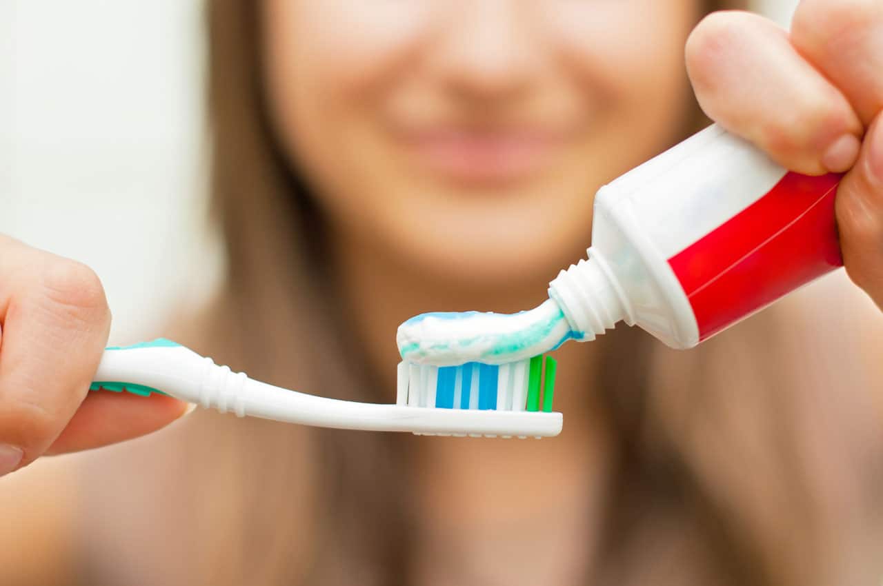 Close up of a woman squeezing toothpaste onto toothbrush