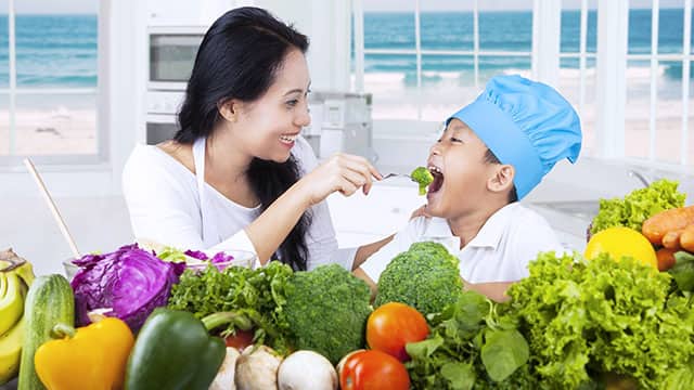 Mom feeding her son with nutritional food good for teeth