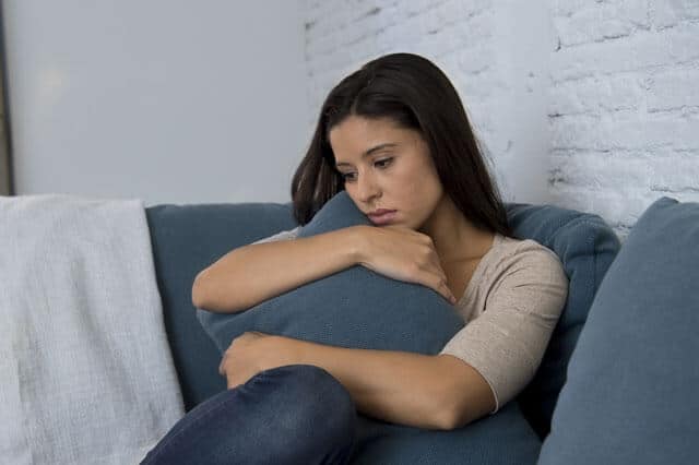 Mujer joven triste con dolor abrazando un cojin