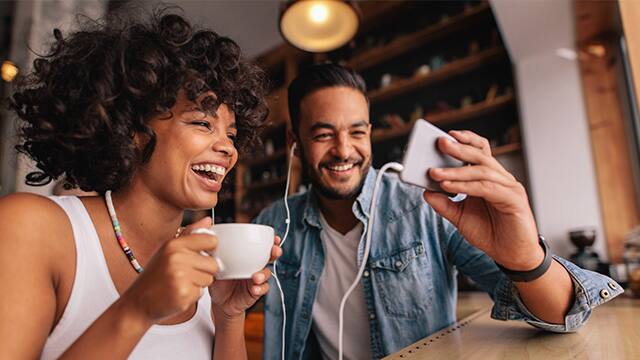 Young man showing something on cellphone to his girlfriend at cafe