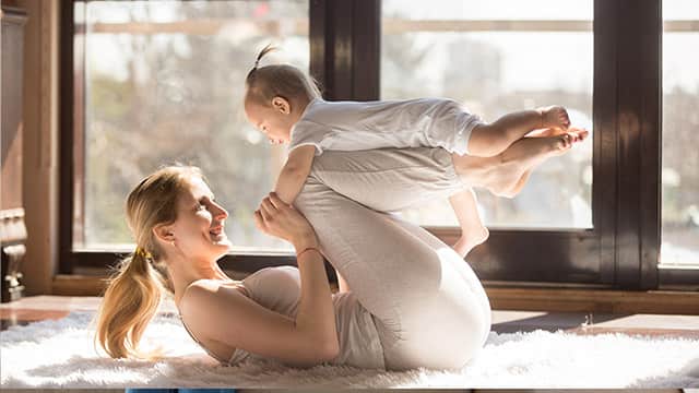 Young sporty mother and baby working out, exercising together at home. wearing white