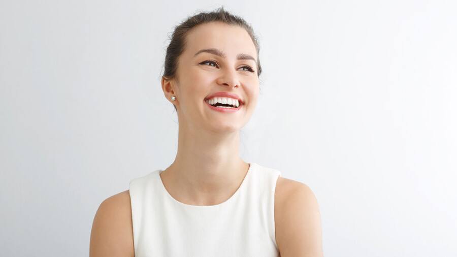 a woman is smiling with healthy teeth after whitening treatment