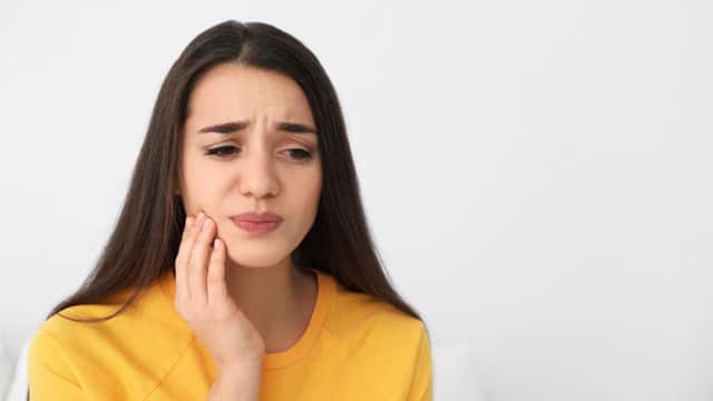 Mujer joven sufriendo de dolor fuerte en los dientes