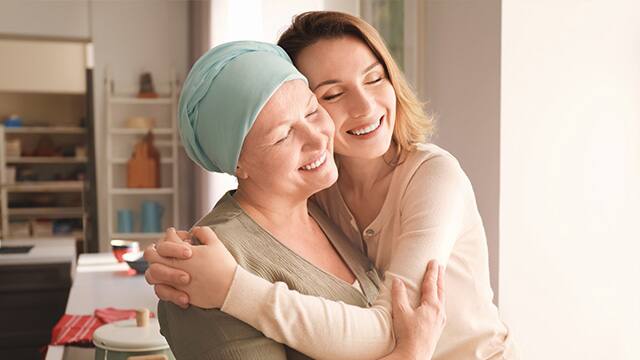 Young woman and mother who has on a headwrap hugging Young woman and mother who has on a headwrap hugging
