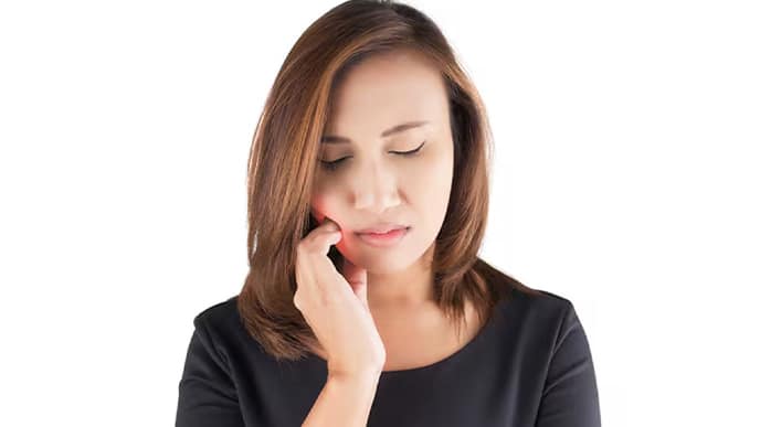 Woman touching her cheek in discomfort showing a common tooth ache cause