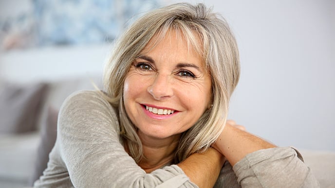 Smiling senior woman sitting in couch at home