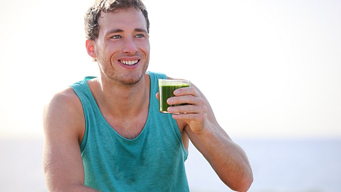 man drinking a green juice