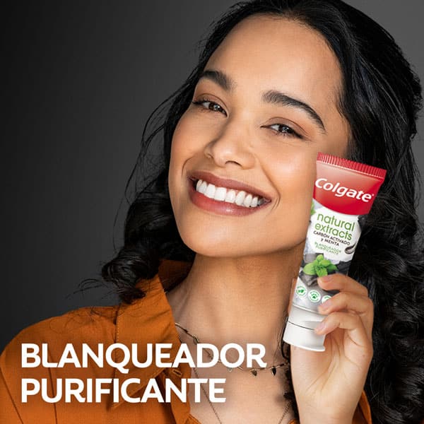 Mujer sosteniendo la crema dental Colgate Natural Extracts Carbón activado y menta