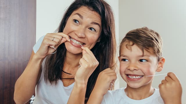 woman and little boy flossing in mirror