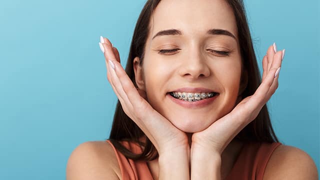 Smilling teenager with braces resting head in hands with eyes closed