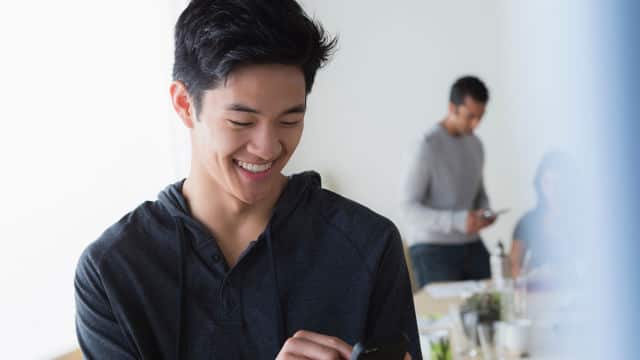 man smiling brightly while looking at his phone