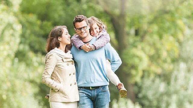 family of three walking through park