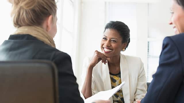 Three women smiling while having a meeting