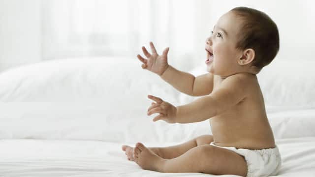 infant sitting on bed