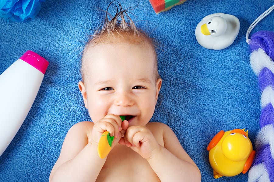 a baby is happy in bed after first teeth brush with toothpaste