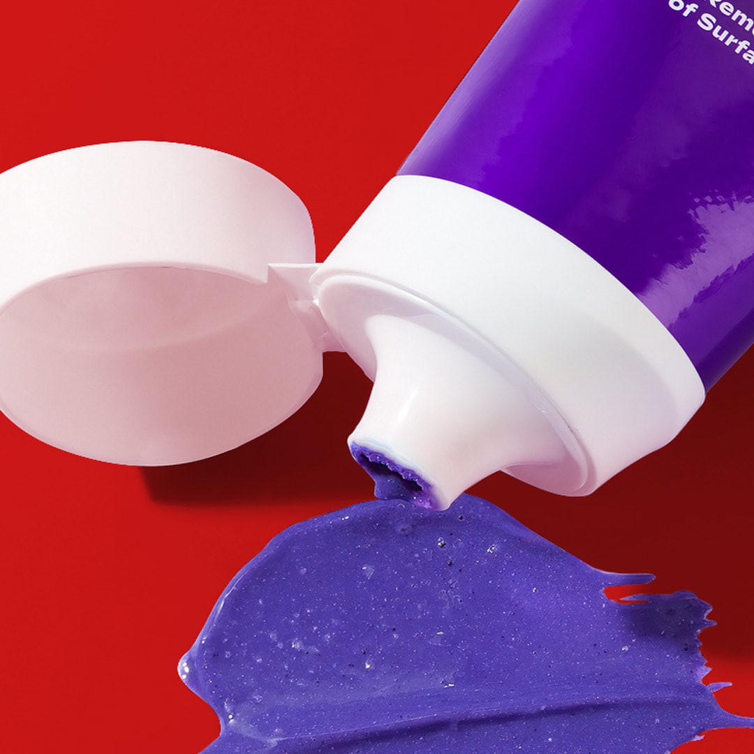 Colgate Optic White Purple Whitening Toothpaste with the power of purple brighteners squirting out into a red background