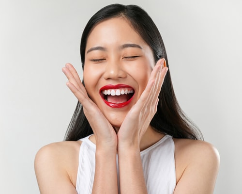 A young happy woman looking very cheerful placing her palms on either side of her face expressing happiness