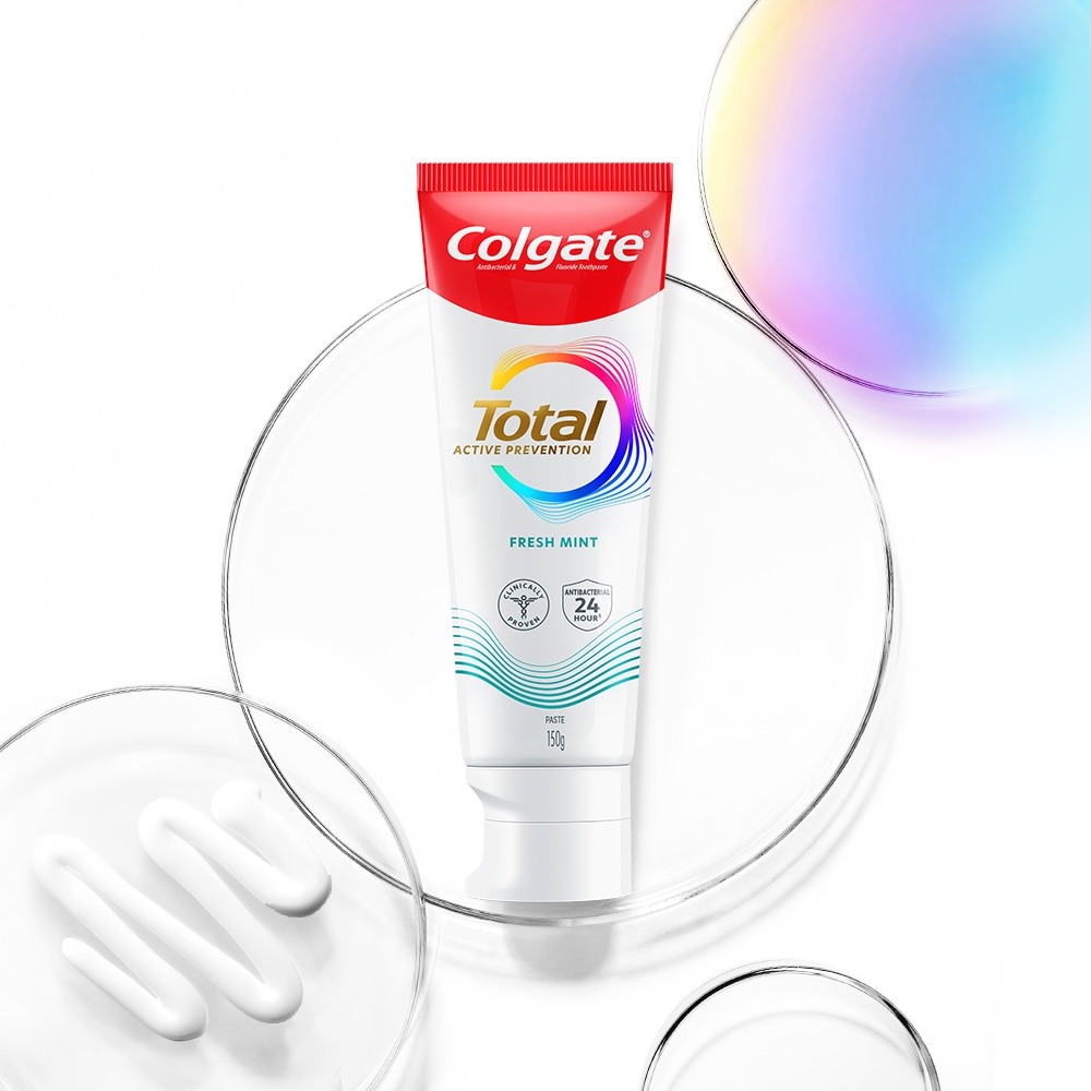 Colgate Total toothpaste tube in the foreground, with transparent and spectrum bubbles in the background